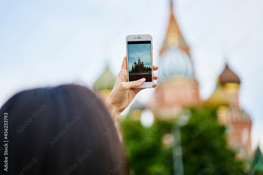Millennial blogger using smartphone technology for taking pictures of cityscape in historic center, unrecognizable woman focus mobile camera on architecture building for making travel photos
