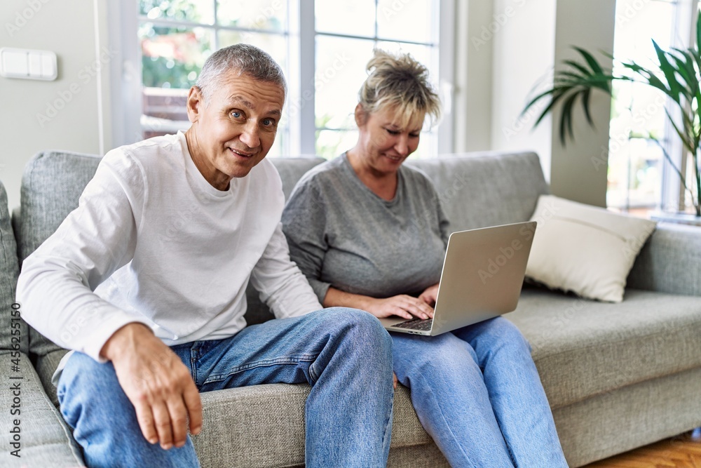 Senior caucasian couple smiling happy using laptop sitting on the sofa at home. Senior caucasian couple smiling happy using laptop sitting on the sofa at home.