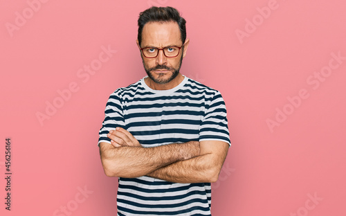 Middle age man wearing casual clothes and glasses skeptic and nervous, disapproving expression on face with crossed arms. negative person.