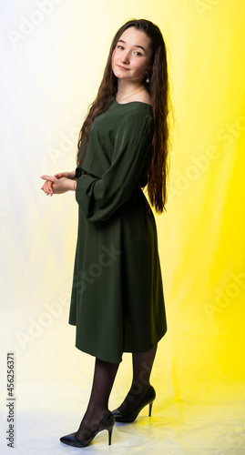full-length portrait of a girl. model in a green dress, black shoes. long curly hair. colored background. © Ольга Новицкая