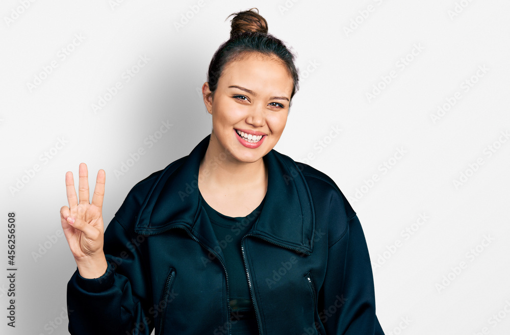 Young hispanic girl wearing sportswear showing and pointing up with fingers number three while smiling confident and happy.