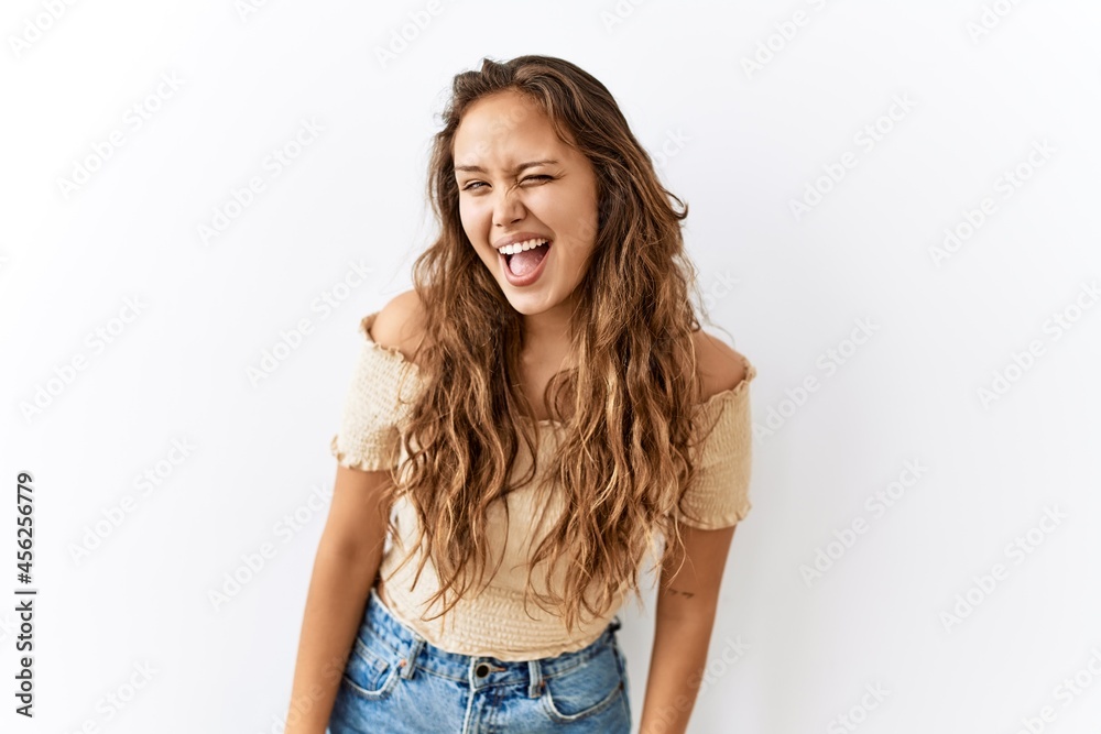 Beautiful hispanic woman standing over isolated while background winking looking at the camera with sexy expression, cheerful and happy face. Beautiful hispanic woman standing over isolated while background winking looking at the camera with sexy expression, cheerful and happy face.