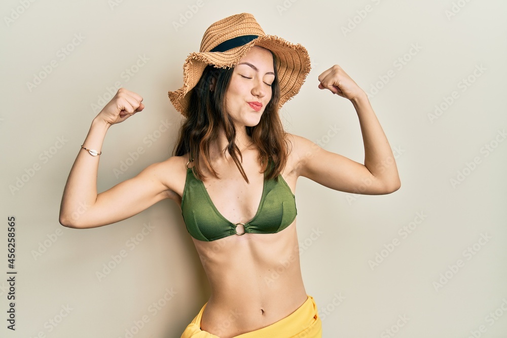 Young brunette woman wearing bikini showing arms muscles smiling proud. fitness concept. Young brunette woman wearing bikini showing arms muscles smiling proud. fitness concept.