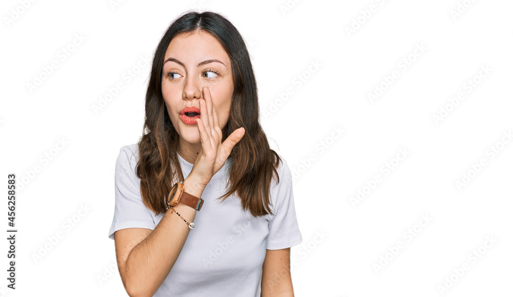 Young beautiful woman wearing casual white t shirt hand on mouth telling secret rumor, whispering malicious talk conversation Young beautiful woman wearing casual white t shirt hand on mouth telling secret rumor, whispering malicious talk conversation