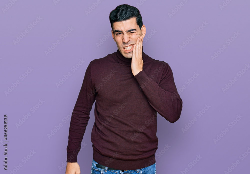 Handsome hispanic man wearing casual turtleneck sweater touching mouth with hand with painful expression because of toothache or dental illness on teeth. dentist Handsome hispanic man wearing casual turtleneck sweater touching mouth with hand with painful expression because of toothache or dental illness on teeth. dentist