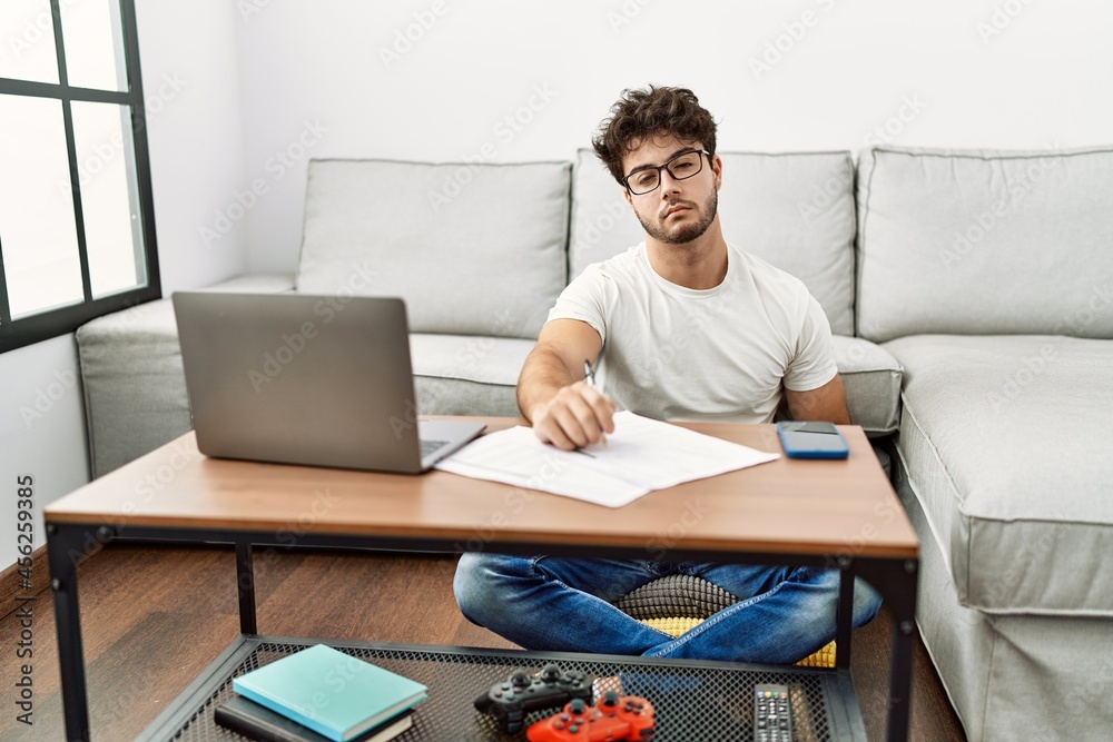 Hispanic man doing papers at home looking sleepy and tired, exhausted for fatigue and hangover, lazy eyes in the morning.