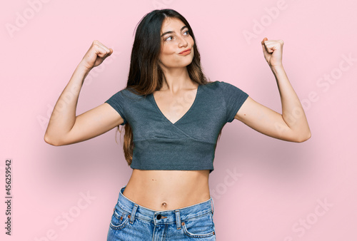 Fotografiet Young beautiful teen girl wearing casual crop top t shirt showing arms muscles smiling proud
