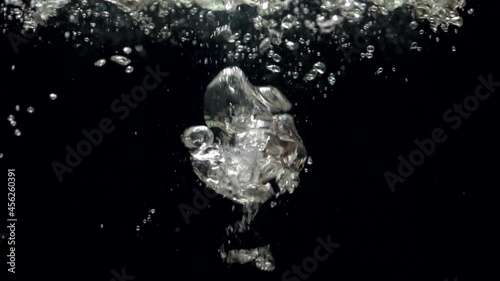Slow motion air bubbles in water rising up to the surface on isolated black background. Slowmotion air bubbles floating under transparent water bubbles in aquarium