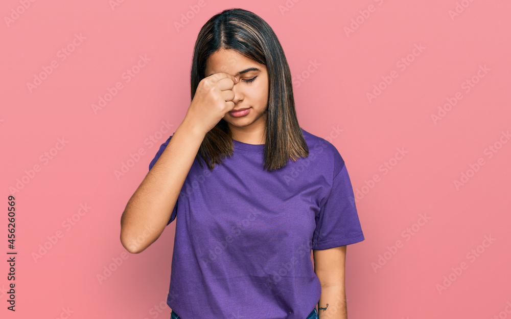 Young hispanic girl wearing casual purple t shirt tired rubbing nose and eyes feeling fatigue and headache. stress and frustration concept.