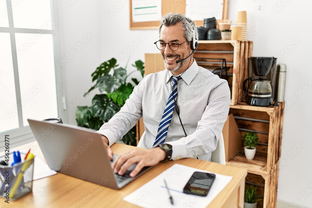 Middle age hispanic business man working at the office wearing operator headset with a happy and cool smile on face. lucky person. Middle age hispanic business man working at the office wearing operator headset with a happy and cool smile on face. lucky person.