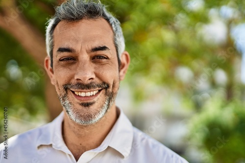 Middle age grey-haired man smiling happy standing at the city.