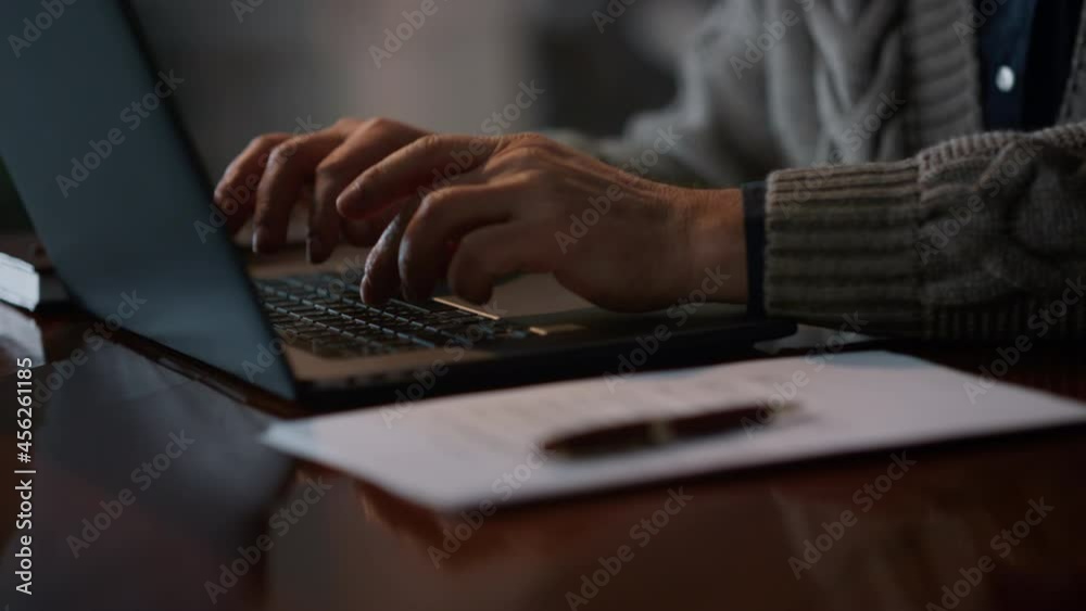 Closeup old man hands typing on computer at home. Male arms using laptop indoors