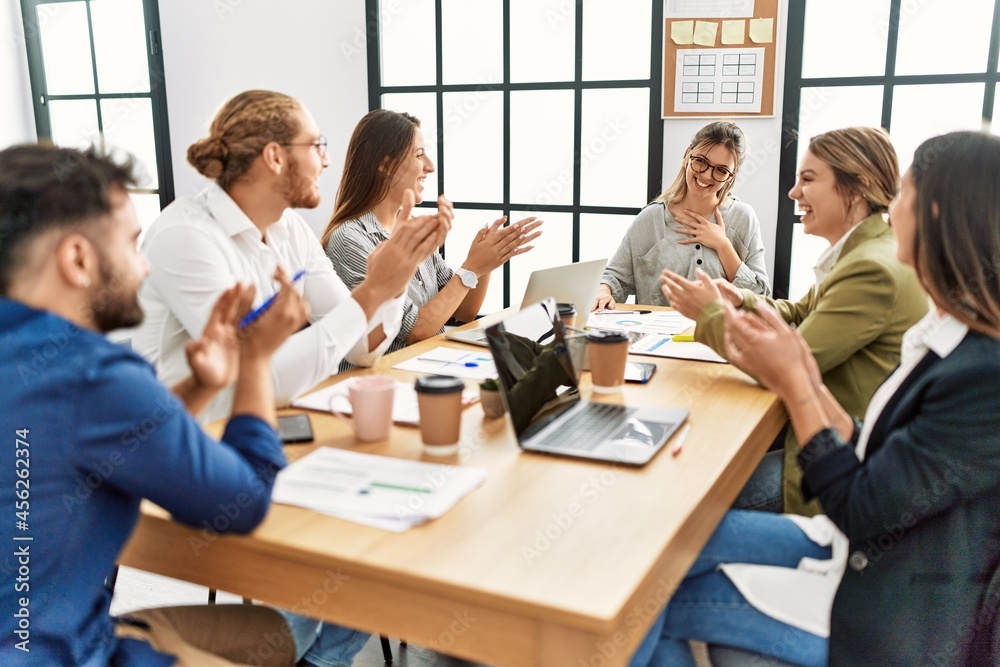 Group of business workers smiling and clapping to partner at the office.