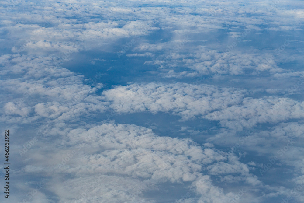 Fototapeta premium Stratosphere, a view of clouds from an airplane window. Cumuliform cloudscape on sky. Flying over the land.