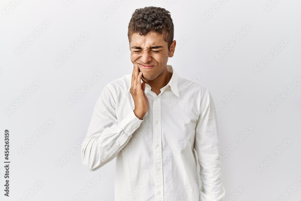 Young handsome hispanic man standing over isolated background touching mouth with hand with painful expression because of toothache or dental illness on teeth. dentist Young handsome hispanic man standing over isolated background touching mouth with hand with painful expression because of toothache or dental illness on teeth. dentist