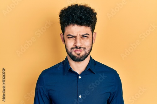 Young arab man with beard wearing casual shirt puffing cheeks with funny face. mouth inflated with air, crazy expression.