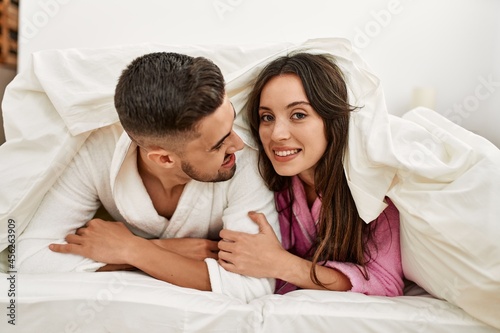 Young hispanic couple smiling happy lying in bed at home.