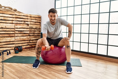 Young hispanic man smiling confident training at sport center
