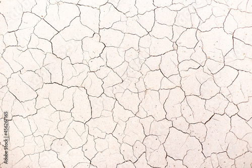 The texture of dry cracked white clay. There are many cracks in the ground.