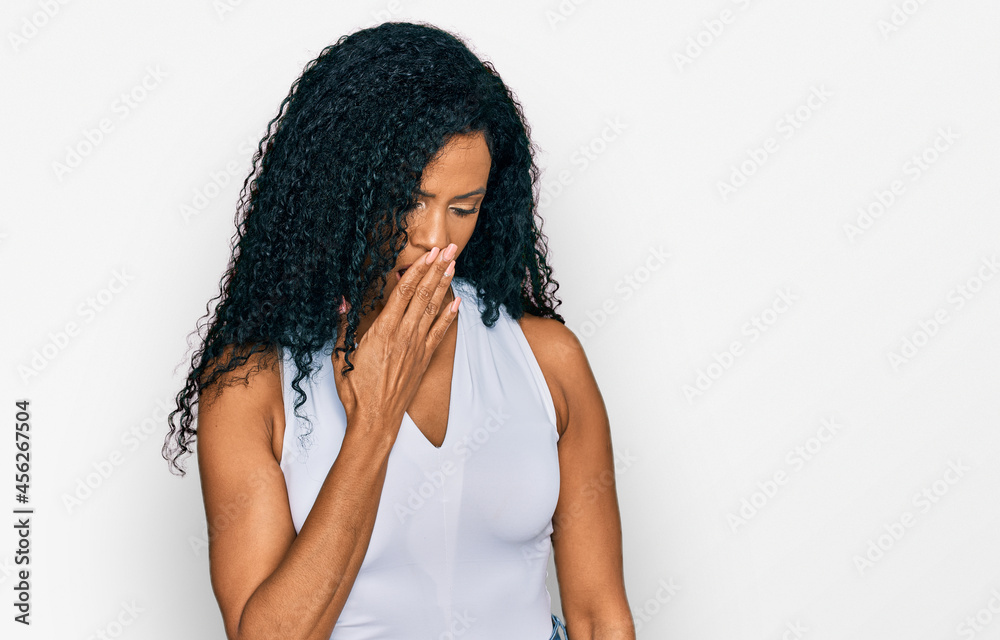 Middle age african american woman wearing casual style with sleeveless shirt bored yawning tired covering mouth with hand. restless and sleepiness.