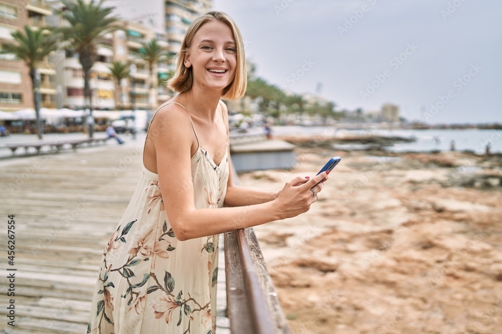 Young beautiful woman using smartphone by the sea
