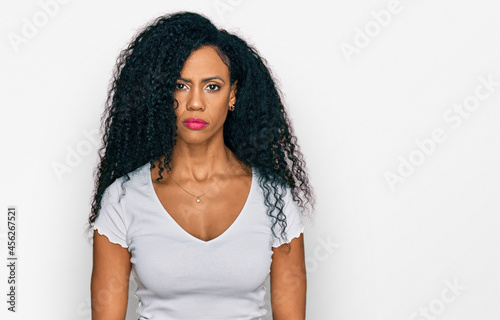 Middle age african american woman wearing casual white t shirt relaxed with serious expression on face. simple and natural looking at the camera.