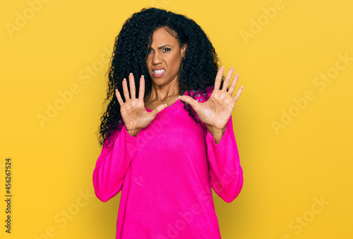 Middle age african american woman wearing casual clothes afraid and terrified with fear expression stop gesture with hands, shouting in shock. panic concept.