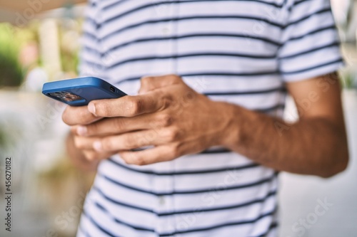 Young hispanic man using smartphone at street