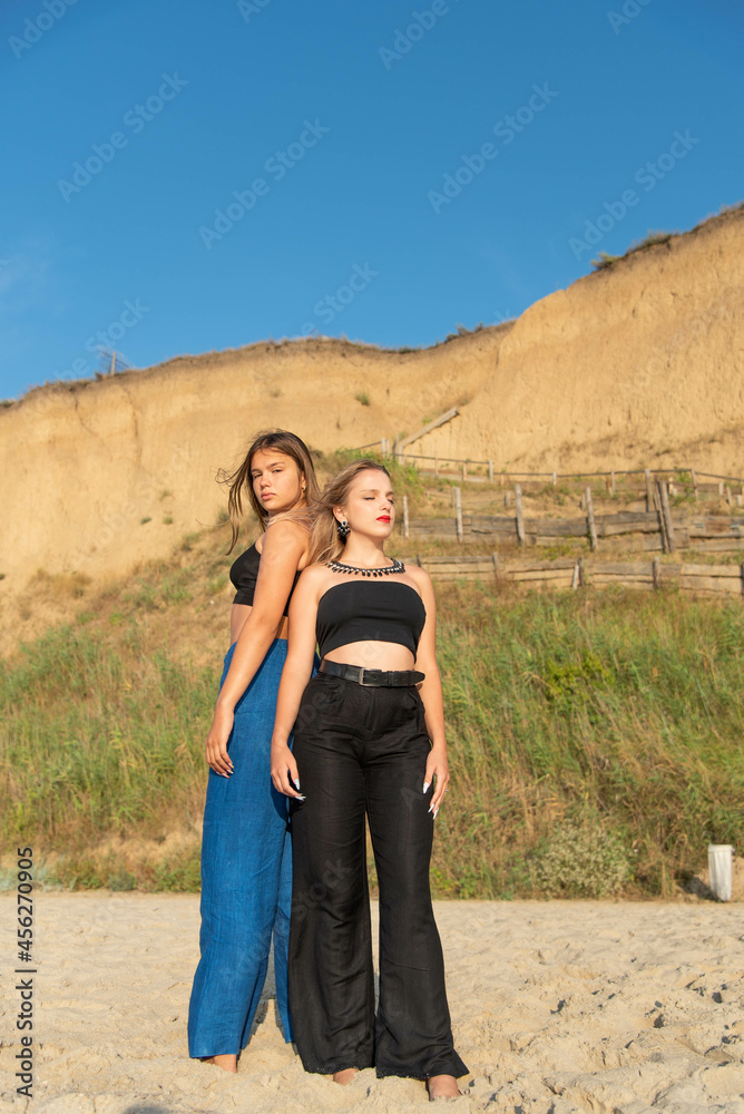 Naklejka premium Happy young people running on beach and enjoying summer holiday. two young beautiful girls walking on beach