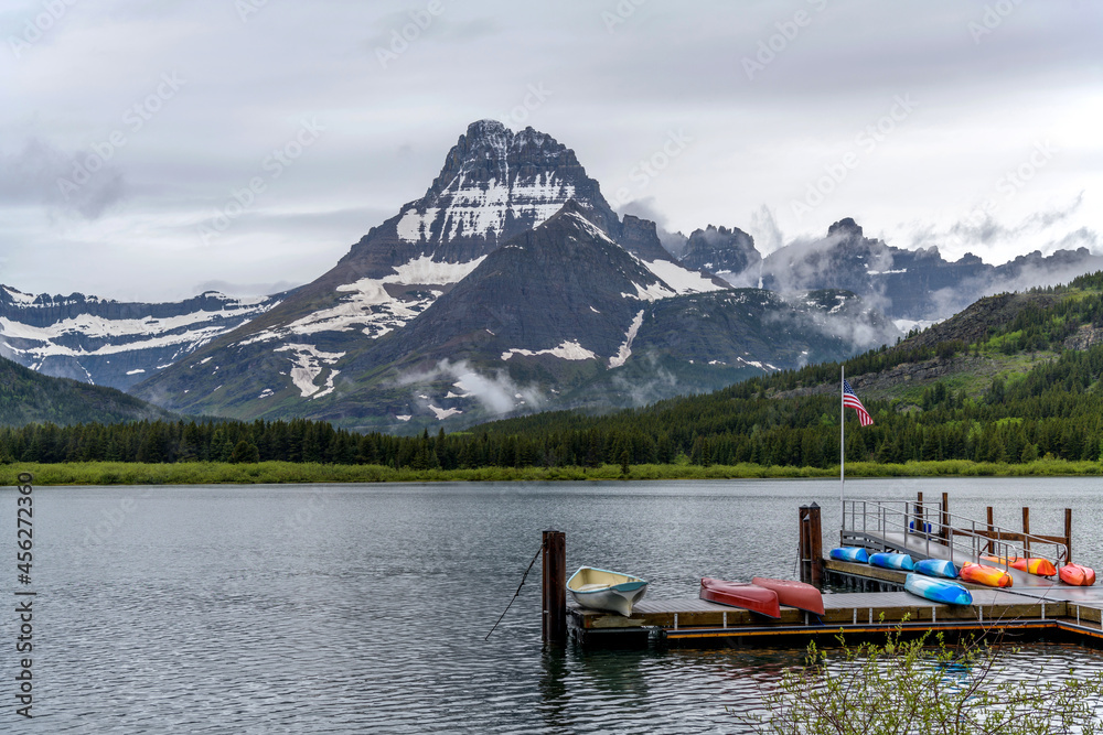 Swiftcurrent Lake - A U.S. Flag flying above a boat launch at Swiftcurrent Lake, with Mt. Wilbur towering at west shore, on a stormy Spring morning. Many Glacier, Glacier National Park, Montana, USA.