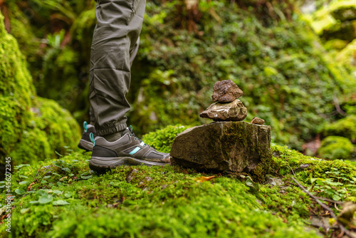 sports shoes for hiking on mossy rock. Stones indicating the way of a mountain path.