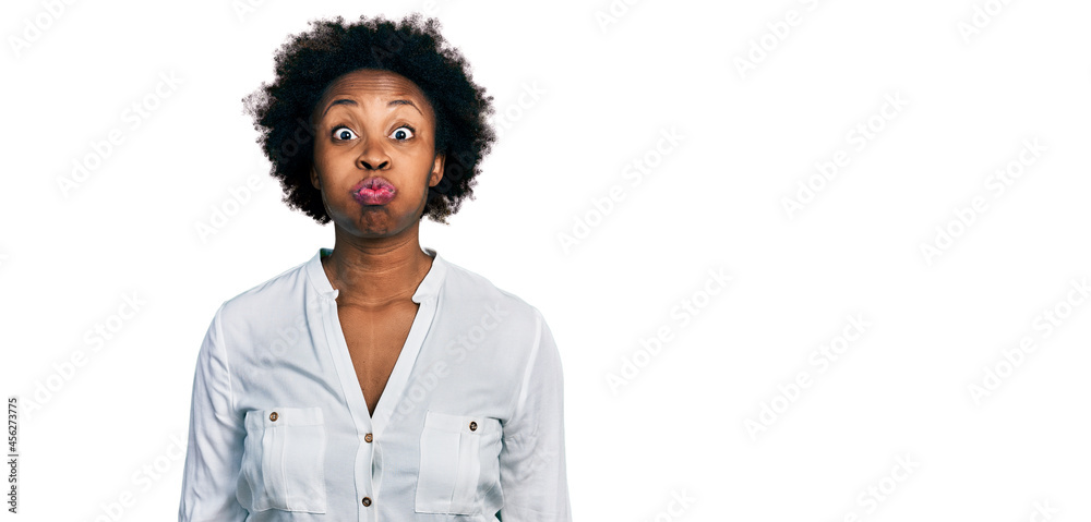 African american woman with afro hair wearing casual white t shirt puffing cheeks with funny face. mouth inflated with air, crazy expression. African american woman with afro hair wearing casual white t shirt puffing cheeks with funny face. mouth inflated with air, crazy expression.