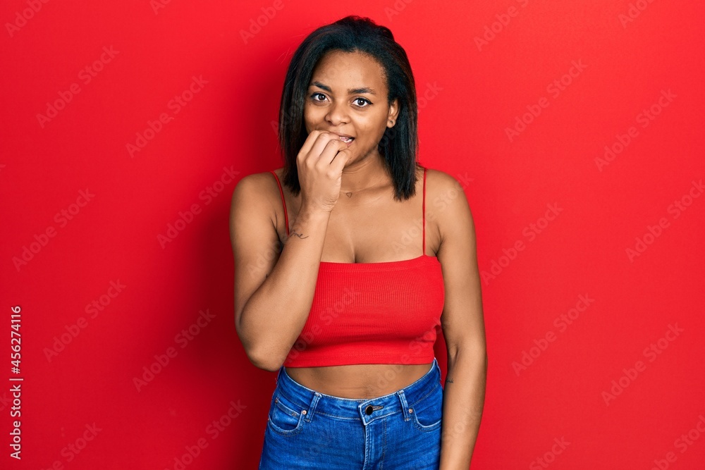Young african american girl wearing casual style with sleeveless shirt looking stressed and nervous with hands on mouth biting nails. anxiety problem. Young african american girl wearing casual style with sleeveless shirt looking stressed and nervous with hands on mouth biting nails. anxiety problem.