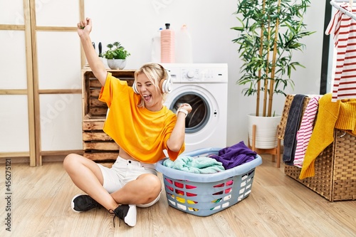 Fotografia Young blonde girl doing laundry listening to music at home.