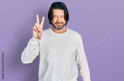 Middle age caucasian man wearing casual clothes smiling looking to the camera showing fingers doing victory sign. number two.
