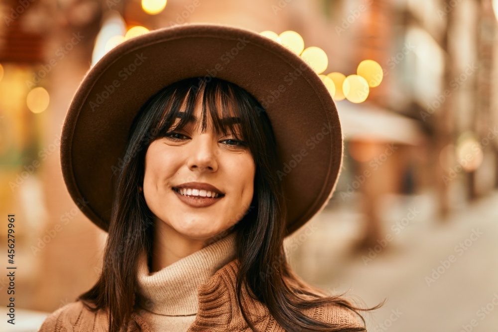 Brunette woman wearing winter hat smiling outdoors at the city Brunette woman wearing winter hat smiling outdoors at the city