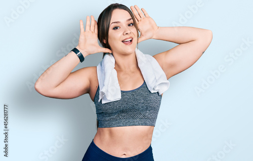 Young hispanic girl wearing sportswear and towel smiling cheerful playing peek a boo with hands showing face. surprised and exited © Krakenimages.com