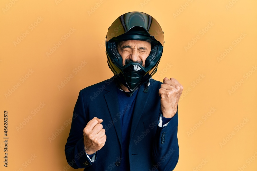 Middle age hispanic man wearing motorcycle helmet celebrating surprised and amazed for success with arms raised and eyes closed