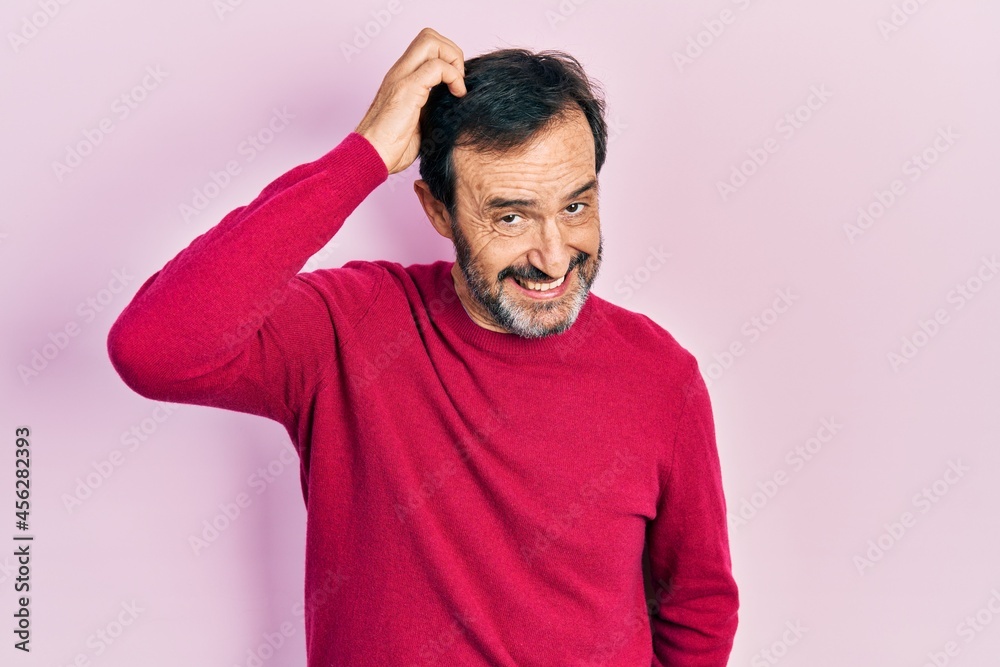 Middle age hispanic man wearing casual clothes confuse and wonder about question. uncertain with doubt, thinking with hand on head. pensive concept. Middle age hispanic man wearing casual clothes confuse and wonder about question. uncertain with doubt, thinking with hand on head. pensive concept.
