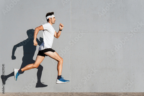 Caucasian young man doing sport jumping, shadow cast on the wall