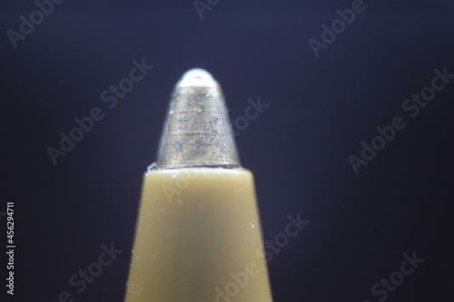 Macro photo of ballpoint pen tip with dark grey background. photo