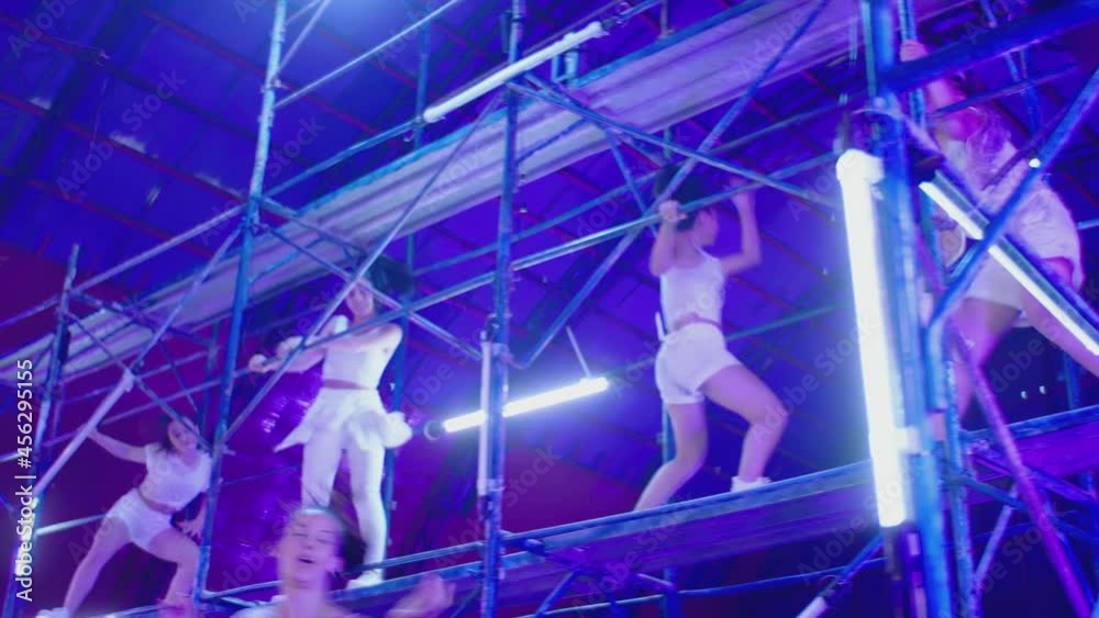 Many female dancers dressed in white shorts dancing inside abandoned