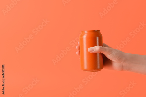 Hand with can of soda on color background