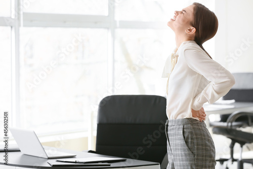 Young businesswoman suffering from back pain in office