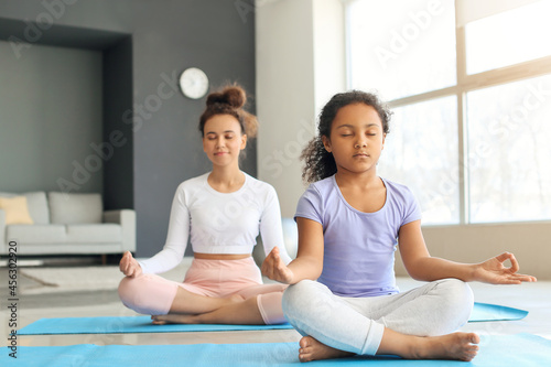 African-American little girl with her mother practicing yoga at home