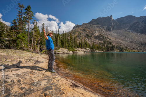 A hiker holding hands up at Lake Nokoni