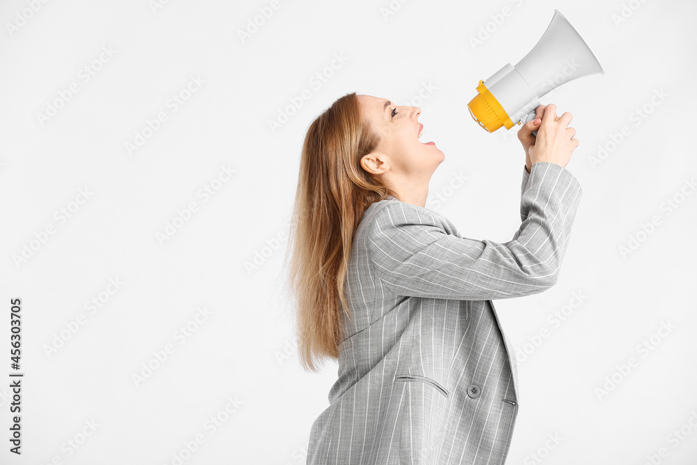 Mature woman shouting into megaphone on white background Mature woman shouting into megaphone on white background