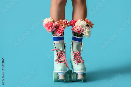 Принти на полотні Legs of young woman in roller skates with flowers on color background