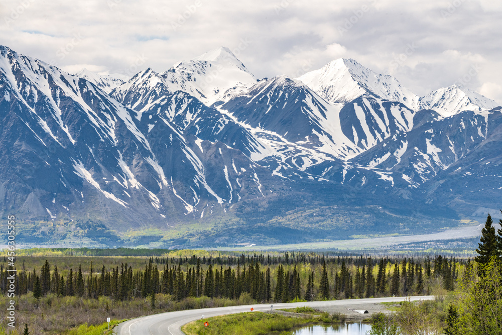 Winding highway beside magnificent mountain peaks in northern Canada, Yukon Territory during summer time, June. 