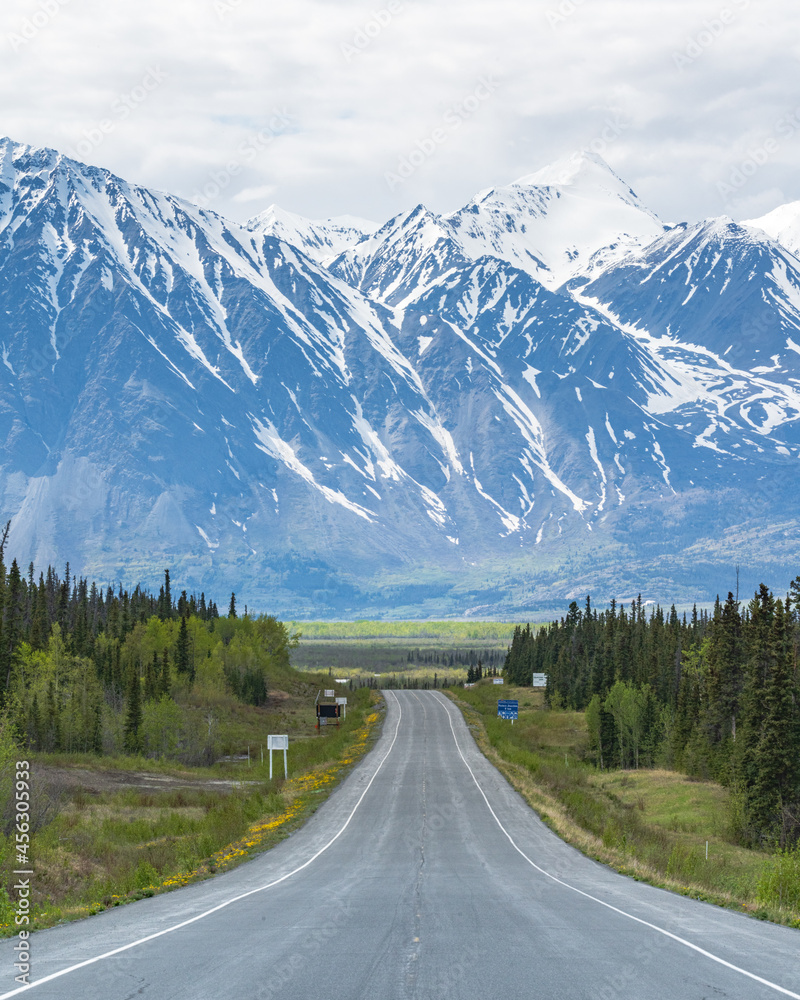 Alaska Highway heading to Haines Junction, Yukon Territory during summer time with huge snow capped mountains. 